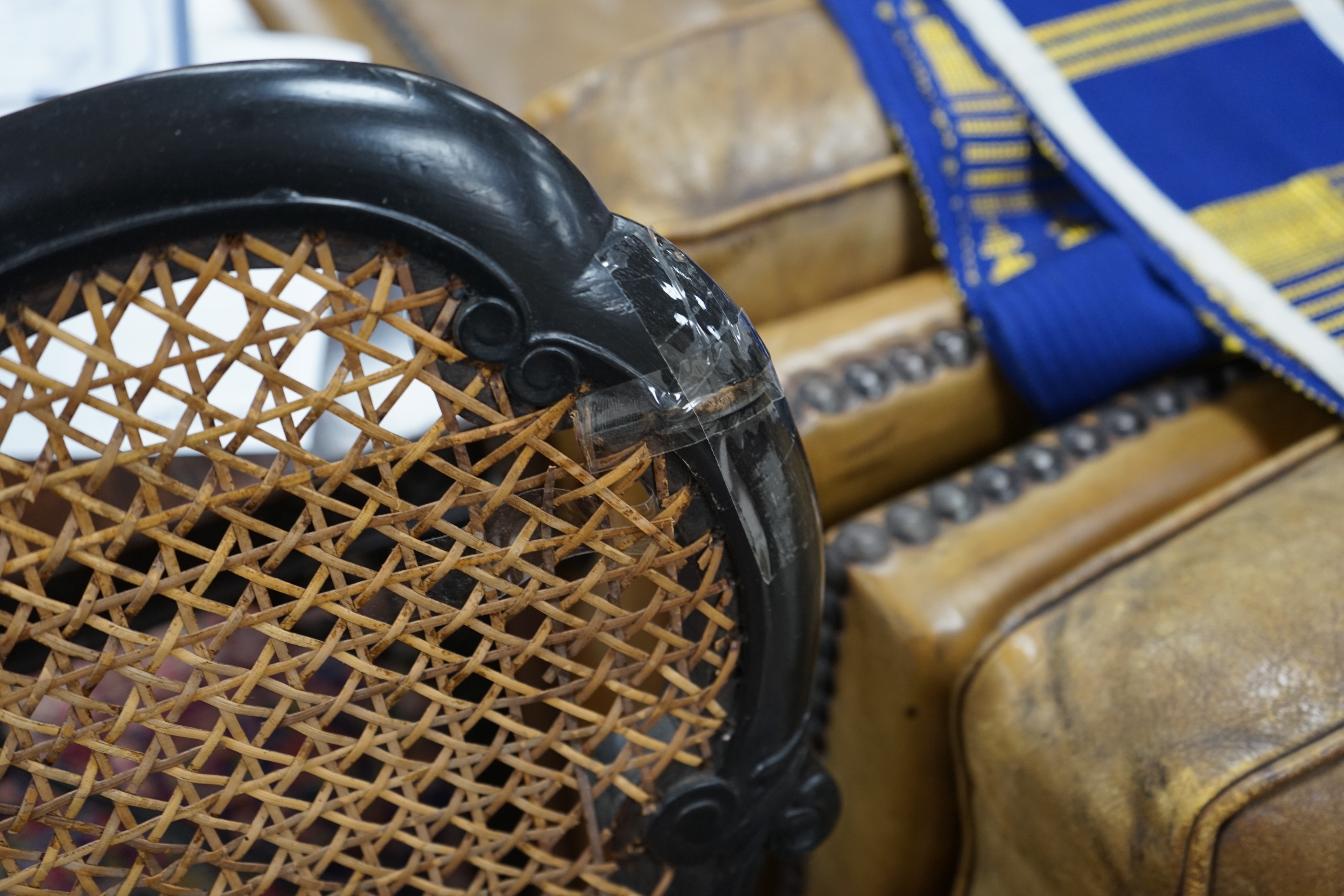 An 18th century style ebonised caned Irish elbow chair, width 70cm, depth 46cm, height 107cm (top rail requires restoration)